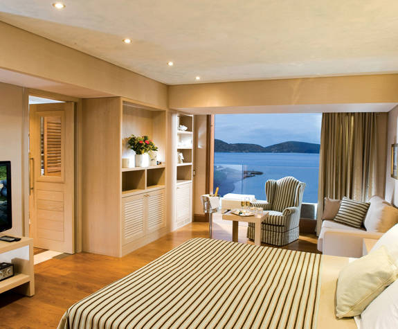 Elounda Bay Palace deluxe hotel suite sea view bed, sofa, armchair and amenities