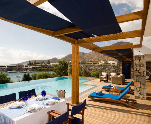 Elounda Bay Palace grand suite table for four, sunbeds and armchairs in front of the pool