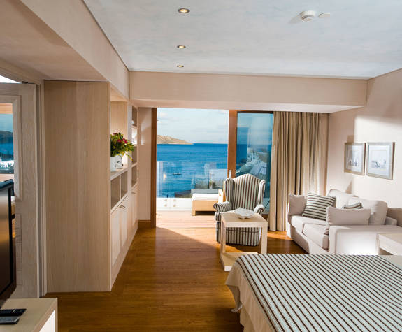 Elounda Bay Palace deluxe hotel suite sea view bed, sofa, armchair and amenities